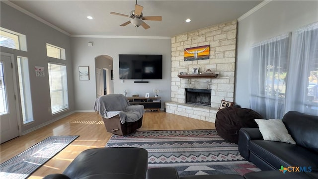 living room with hardwood / wood-style floors, ceiling fan, a fireplace, and crown molding