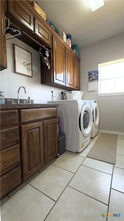 clothes washing area with washing machine and dryer, sink, light tile patterned flooring, and cabinets