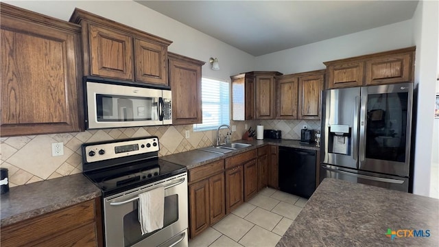 kitchen featuring decorative backsplash, appliances with stainless steel finishes, light tile patterned floors, and sink