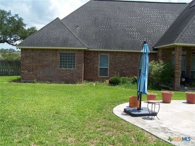 101 Laurel Oak Cir, Cuero, TX 77954 - back of property with a patio, brick siding, and roof with shingles