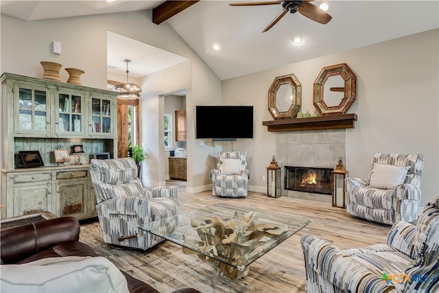 living room with high vaulted ceiling, ceiling fan, a fireplace, beamed ceiling, and light hardwood / wood-style floors