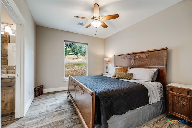 bedroom with hardwood / wood-style floors, ceiling fan, sink, and connected bathroom