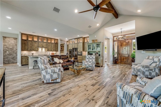 living room with light hardwood / wood-style flooring, lofted ceiling with beams, and ceiling fan with notable chandelier