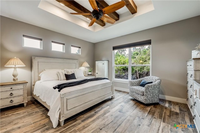 bedroom with beam ceiling, a raised ceiling, ceiling fan, and light hardwood / wood-style floors