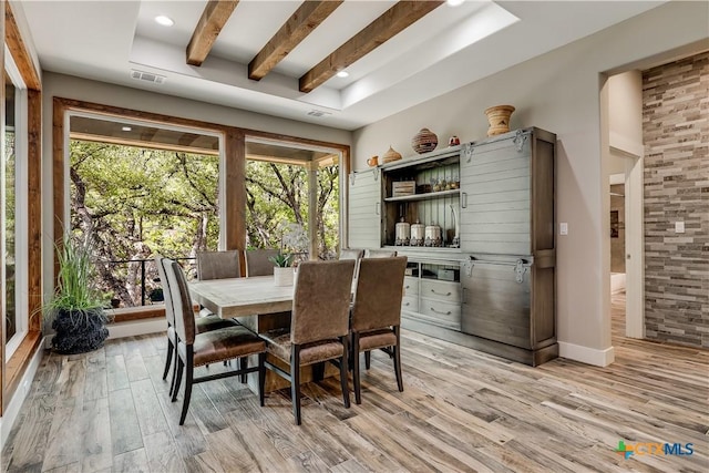 dining space featuring beamed ceiling and light hardwood / wood-style floors