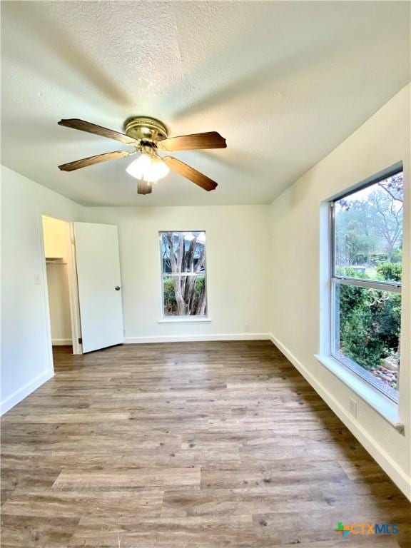 unfurnished room with ceiling fan, light wood-type flooring, and a textured ceiling