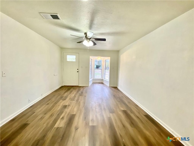 unfurnished room featuring a textured ceiling, ceiling fan, and dark wood-type flooring