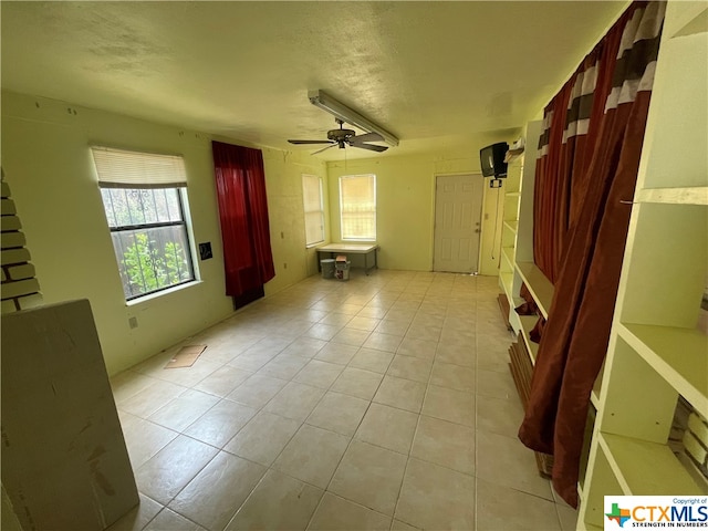 unfurnished living room featuring ceiling fan and light tile patterned floors