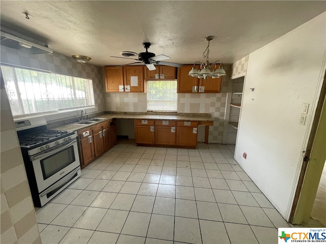 kitchen with sink, tasteful backsplash, ceiling fan with notable chandelier, gas range, and hanging light fixtures