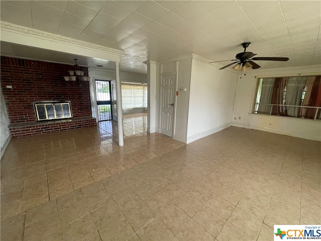 unfurnished living room with a brick fireplace, brick wall, ceiling fan, and ornate columns