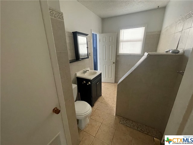 bathroom featuring tile patterned flooring, vanity, toilet, and a textured ceiling