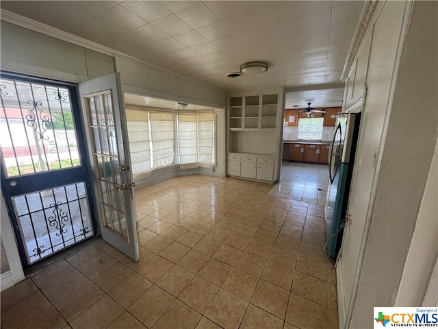 interior space featuring ceiling fan, a healthy amount of sunlight, light tile patterned floors, and ornamental molding