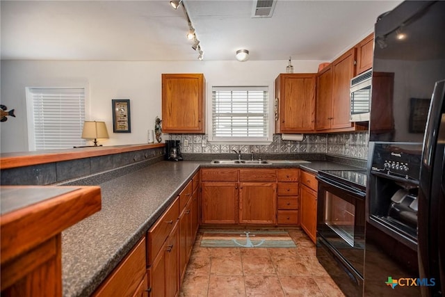 kitchen with sink, light tile patterned floors, backsplash, black appliances, and kitchen peninsula