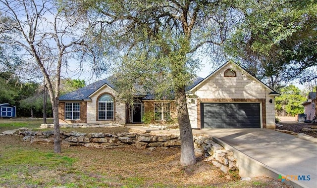 single story home featuring concrete driveway, an attached garage, an outdoor structure, a shed, and brick siding