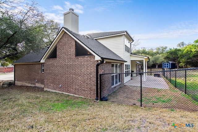 view of side of property featuring a yard, brick siding, a patio area, and fence