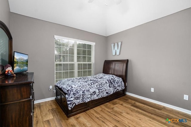 bedroom featuring lofted ceiling, wood finished floors, and baseboards