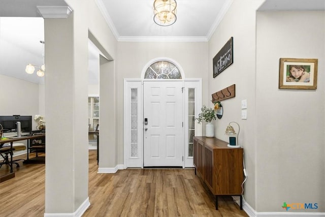 entrance foyer featuring baseboards, crown molding, a chandelier, and wood finished floors