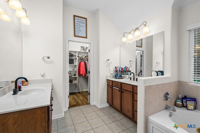 full bath with a healthy amount of sunlight, tile patterned flooring, two vanities, and a sink