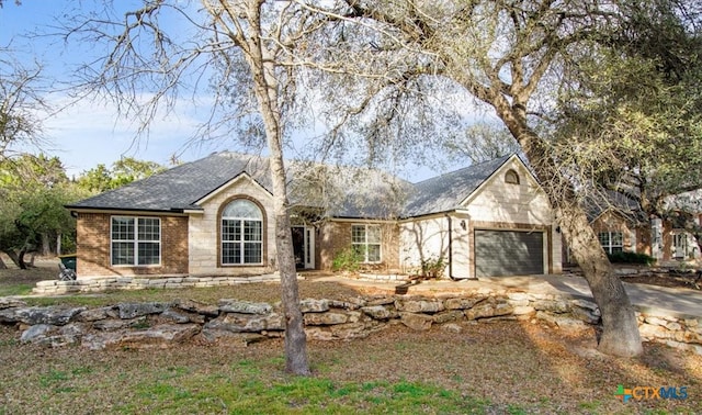 ranch-style home with an attached garage, driveway, roof with shingles, and brick siding