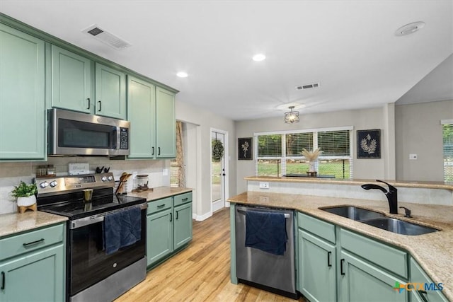 kitchen with appliances with stainless steel finishes, visible vents, a sink, and green cabinets