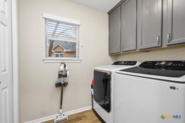 laundry area with baseboards, wood finished floors, cabinet space, and washer and dryer