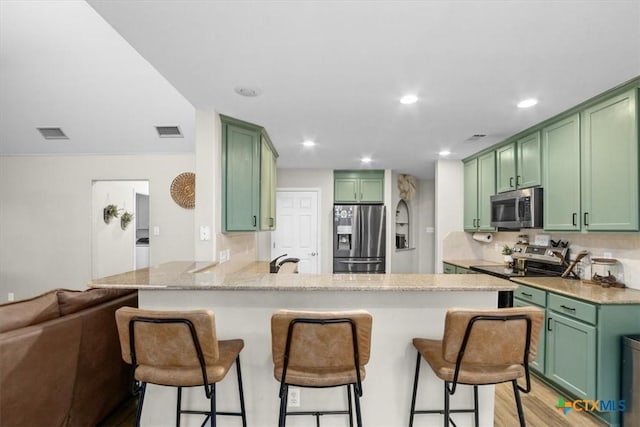 kitchen with green cabinets, stainless steel appliances, and a peninsula