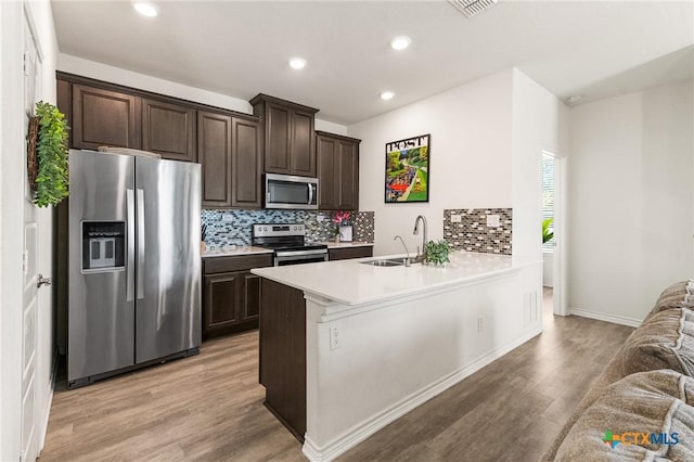 14902 Ardilla, San Antonio, TX 78217 - kitchen with stainless steel appliances, dark brown cabinets, a sink, light wood-type flooring, and decorative backsplash