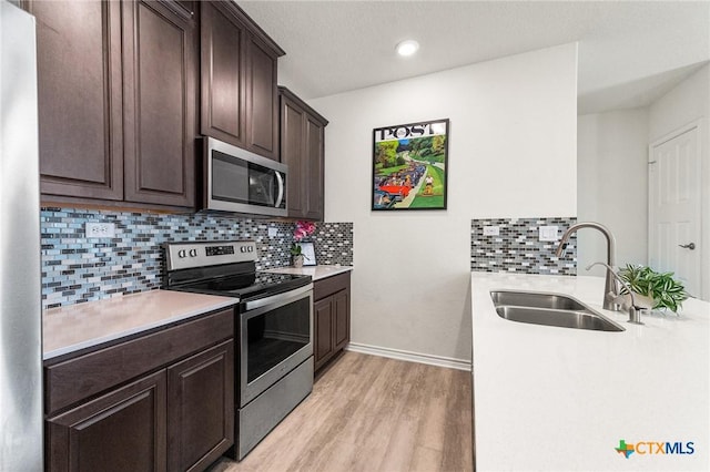 14902 Ardilla, San Antonio, TX 78217 - kitchen featuring stainless steel appliances, a sink, light wood-style floors, dark brown cabinets, and light countertops