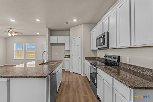 702 Stonevalley Rd, Temple, TX 76502 - kitchen featuring appliances with stainless steel finishes, wood finished floors, white cabinetry, a ceiling fan, and dark stone countertops
