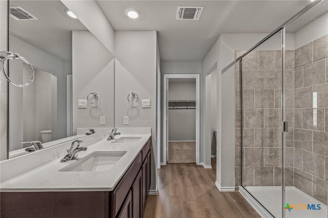 702 Stonevalley Rd, Temple, TX 76502 - bathroom with double vanity, wood finished floors, a stall shower, and a walk in closet