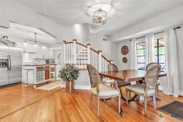 dining room featuring sink, light wood-type flooring, and an inviting chandelier