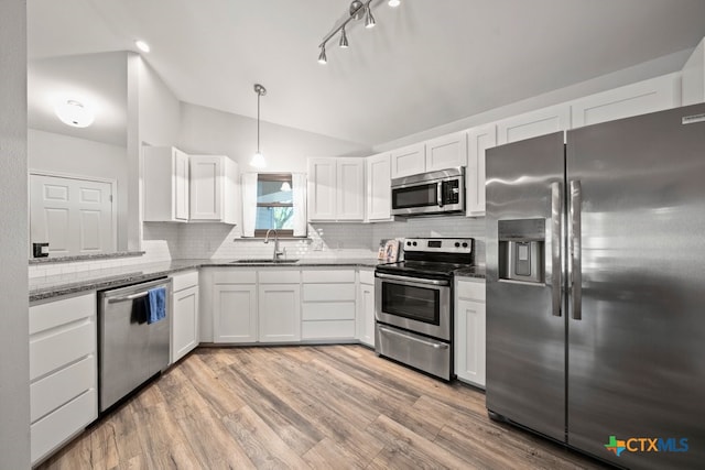 kitchen with appliances with stainless steel finishes, backsplash, white cabinets, light hardwood / wood-style floors, and hanging light fixtures