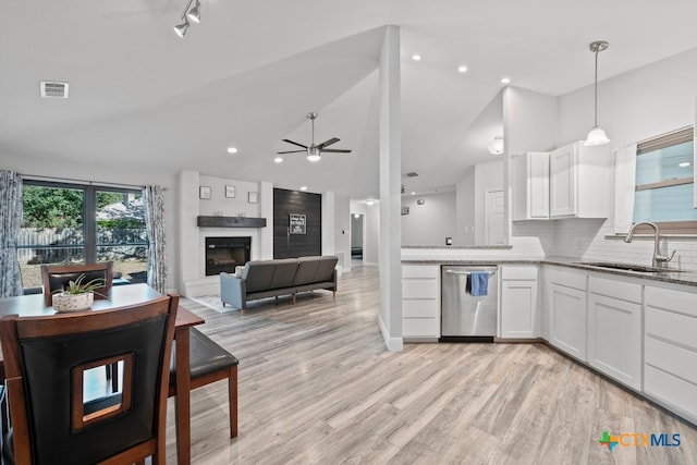 kitchen featuring a large fireplace, sink, stainless steel dishwasher, decorative light fixtures, and white cabinets