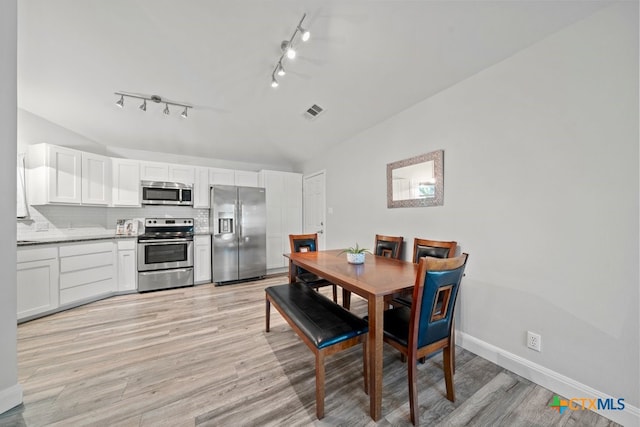 dining area featuring lofted ceiling and light wood-type flooring