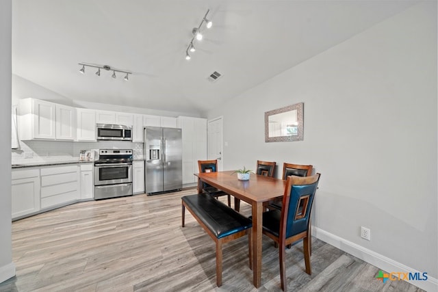 309 Paisano St, New Braunfels, TX 78130 - dining space featuring rail lighting, lofted ceiling, light wood-type flooring, and baseboards