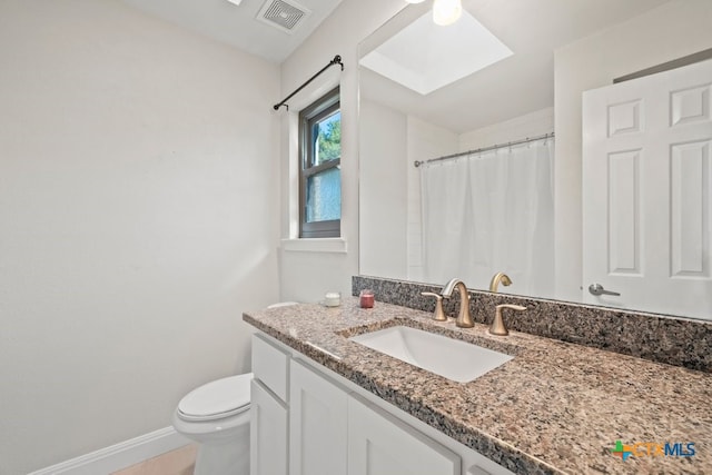 bathroom with a skylight, a shower with curtain, vanity, and toilet