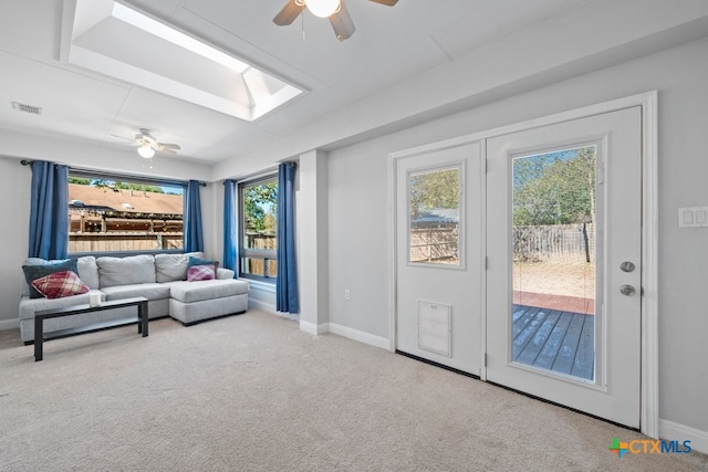 carpeted living room featuring ceiling fan and a skylight