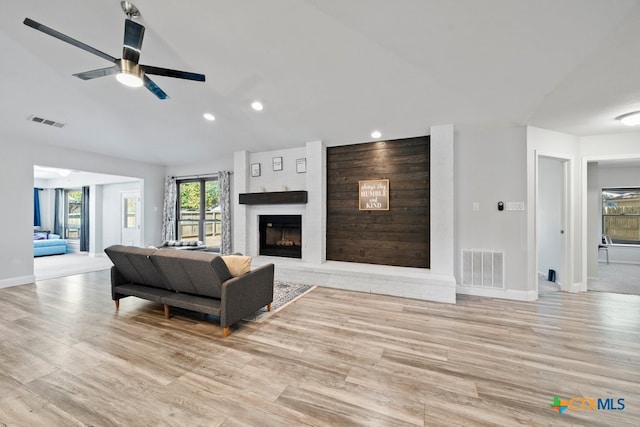 living room with a large fireplace, ceiling fan, light hardwood / wood-style floors, and lofted ceiling