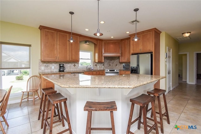 1588 W Bayshore Dr, Palacios, TX 77465 - kitchen with stainless steel appliances, light tile patterned flooring, decorative backsplash, a sink, and brown cabinets