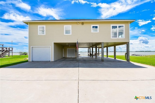 1588 W Bayshore Dr, Palacios, TX 77465 - coastal inspired home with a carport, concrete driveway, an attached garage, and a water view