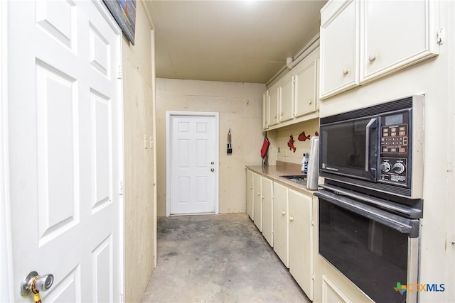 1588 W Bayshore Dr, Palacios, TX 77465 - kitchen featuring black appliances, unfinished concrete floors, light countertops, and white cabinetry