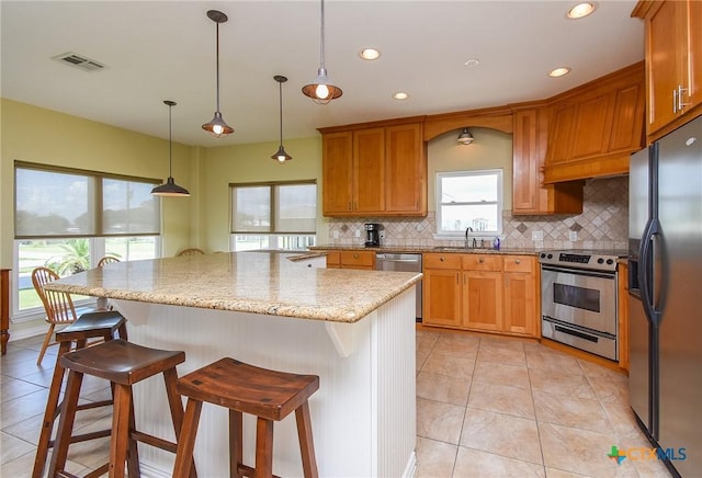 1588 W Bayshore Dr, Palacios, TX 77465 - kitchen with appliances with stainless steel finishes, a sink, tasteful backsplash, a breakfast bar, and light tile patterned floors