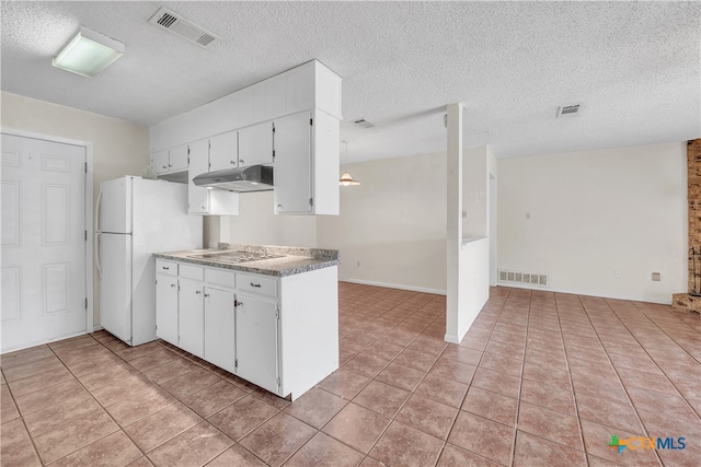 kitchen with a textured ceiling, white fridge, and white cabinets