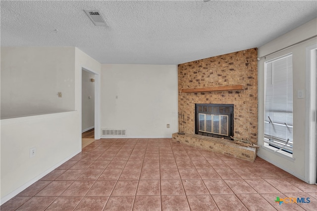 unfurnished living room featuring a fireplace, a textured ceiling, and light tile patterned floors