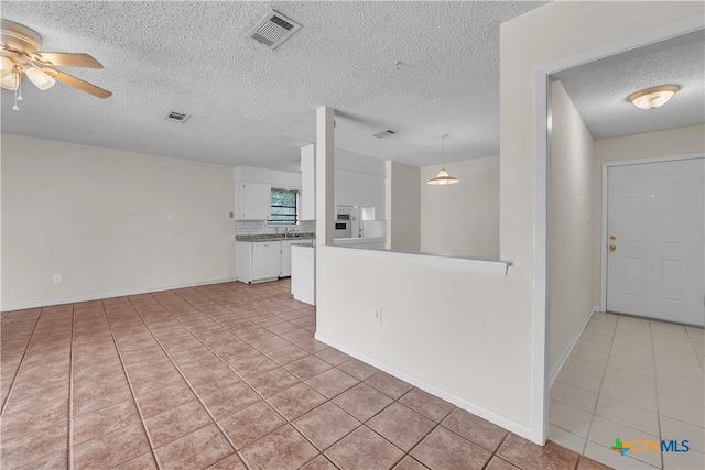 interior space with ceiling fan, a textured ceiling, and light tile patterned floors