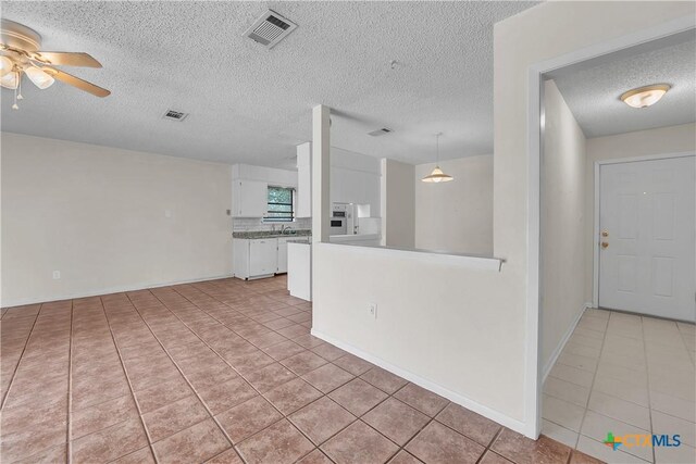 1123 Rhonda Lee St, Copperas Cove, TX 76522 - unfurnished living room with light tile patterned floors, a ceiling fan, a textured ceiling, a sink, and baseboards