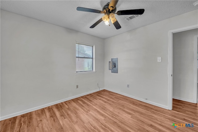 empty room with light wood-type flooring, electric panel, a textured ceiling, and ceiling fan