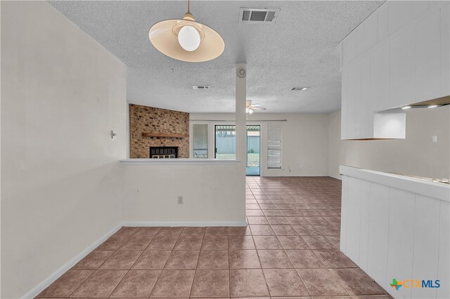 interior space with ceiling fan, a textured ceiling, and a large fireplace