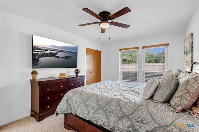 bedroom featuring ceiling fan, light colored carpet, and a textured ceiling