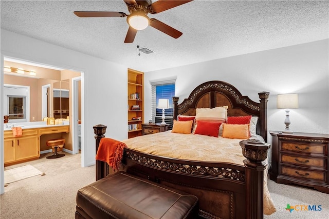 bedroom featuring light carpet, a textured ceiling, ensuite bathroom, and ceiling fan